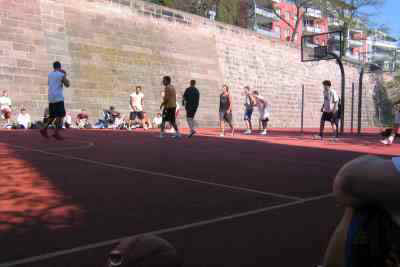 A basketball court, people playing with folks watching.