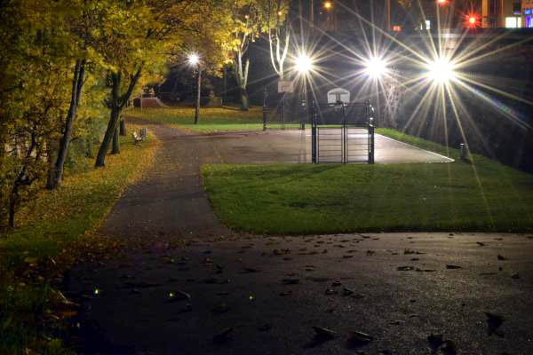 A basketball court near town center at night.